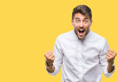 İzole arka plan kutlama üzerinde genç yakışıklı adam şaşırttı ve başarı için kaldırdı kollarını açarak hayret ve gözleri açık. Kazanan kavramı.