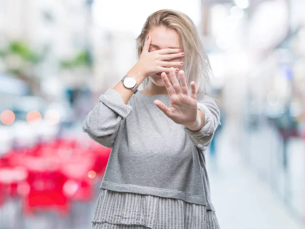 Young blonde woman over isolated background covering eyes with hands and doing stop gesture with sad and fear expression. Embarrassed and negative concept.