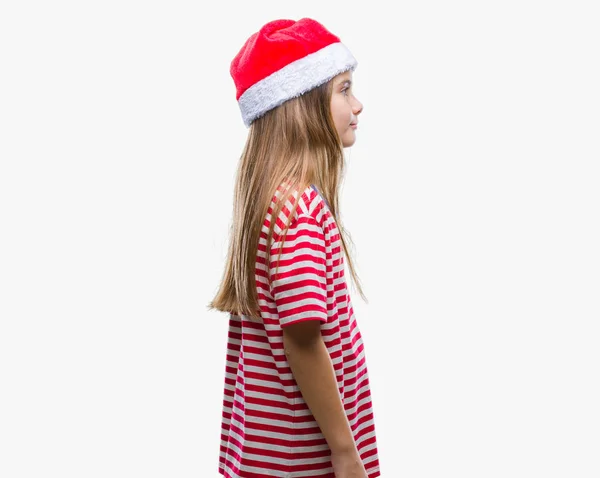 年轻美丽的女孩戴着圣诞节帽子在孤立的背景寻找一边 放松的轮廓姿势与自然脸与自信的微笑 — 图库照片