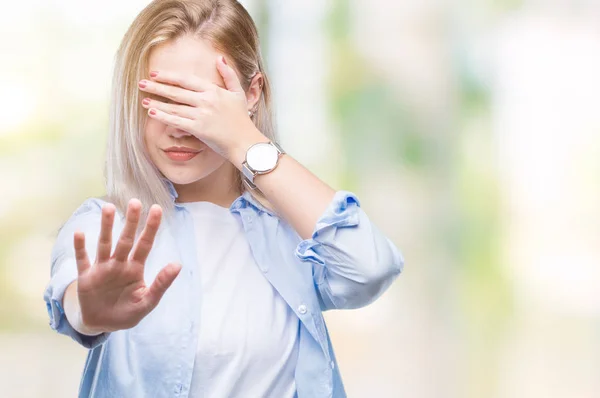 Young blonde woman over isolated background covering eyes with hands and doing stop gesture with sad and fear expression. Embarrassed and negative concept.