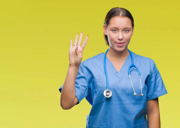 年轻的白种人医生妇女穿医疗制服在孤立的背景显示和指向与手指数字四同时微笑自信和快乐 — 图库照片