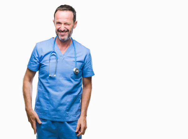 中年老医生男子穿医疗制服在孤立的背景眨眼看着相机与性感的表情 开朗和快乐的脸 — 图库照片