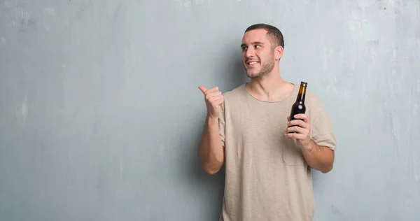 Joven Caucásico Hombre Sobre Gris Grunge Pared Celebración Botella Cerveza —  Fotos de Stock