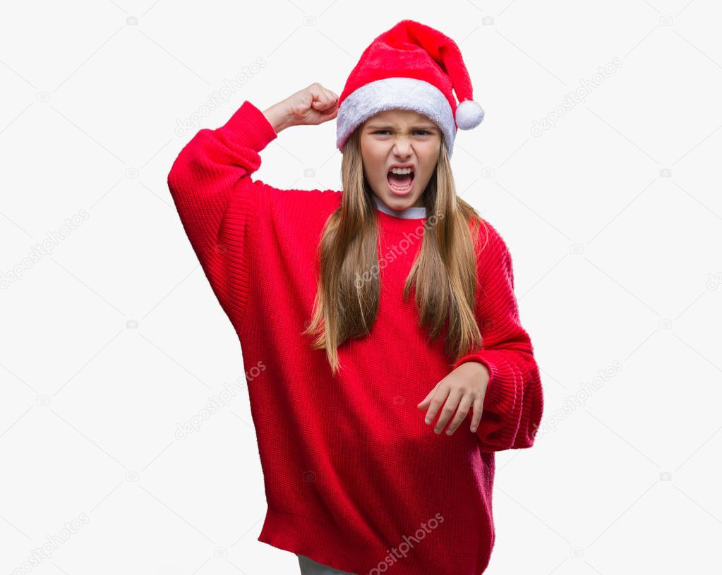 Young beautiful girl wearing christmas hat over isolated background angry and mad raising fist frustrated and furious while shouting with anger. Rage and aggressive concept.