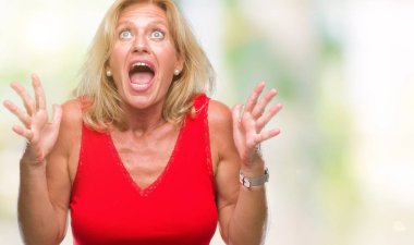 Orta yaş sarışın kadın izole arka plan çılgın ve kızgın bağırarak ve agresif ifade ve silah kaldırdı bağırıyor. Hayal kırıklığı kavramı.