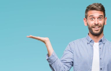 Neşeli sunulması ve kameraya bakarak avucunun ile işaret gülümseyen izole arka plan üzerinde beyaz t-shirt giyen genç yakışıklı adam.