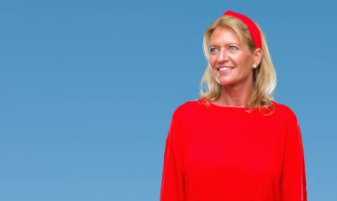 Orta yaş sarışın kadın izole arka plan uzak tarafına gülümseme ile yüzünde, doğal ifade seyir üzerinde. Kendine güvenen gülüyor.