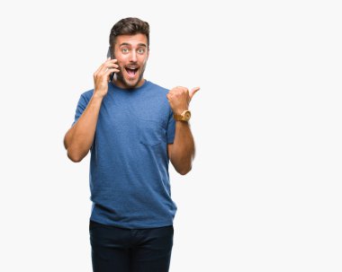 İşaret ve başparmak kadar mutlu yüz gülümseyen tarafı ile gösteren izole arka plan üzerinde Smartphone'da konuşan genç yakışıklı adam