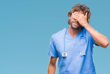 Yakışıklı İspanyol cerrah doktor adam gülümsüyor ve gözleri için sürpriz kapsayan yüz el ile gülüyor izole arka plan. Kör kavramı.