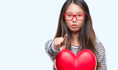 Tutan Genç Asyalı kadın kalp okumak ve kamera için işaret 