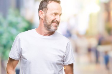 Orta yaş ağarmış komuta sizde üzerinde beyaz t-shirt giyen arka plan uzak tarafına gülümseme ile yüzünde, doğal ifade arıyorum izole. Kendine güvenen gülüyor.