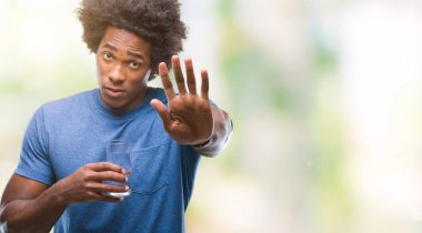 Afro Amerikalı adam dur işareti ile ciddi ve kendine güvenen ifade, savunma hareketi yaparken açık el ile izole arka plan üzerinde bardak su içme