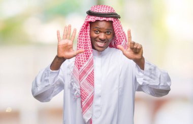 Geleneksel keffiyeh gösterilen ve parmakları ile işaret izole arka plan üzerinde giyen genç Arapça Afrika adam kendinden emin ve mutlu gülümseyerek süre yedi numara.