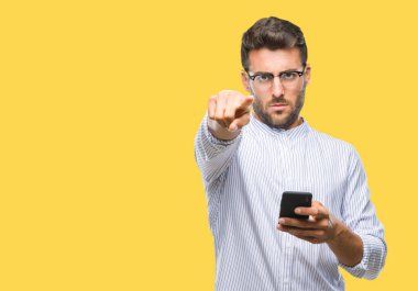 Kamera ve size parmak ile işaret arka plan üzerinde akıllı telefon kullanma yakışıklı delikanlı manifatura izole, el işareti, pozitif ve kendinden emin bir jest ön