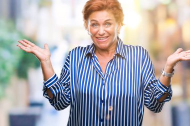 Atrractive üst düzey beyaz Kızıl saçlı kadın izole arka plan clueless ve şaşkın bir ifadeyle kollar ve eller kaldırdı. Şüphe kavramı.