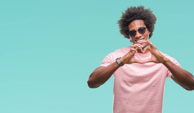 Afro Amerikalı adam aşık kalp simgesi ve elleriyle şekil gösteren gülümseyen izole arka plan üzerinde güneş gözlüğü takıyor. Romantik kavramı.