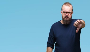 Genç beyaz hipster adam mutsuz ve kızgın ret gösterilen ve başparmak aşağı hareketi ile negatif seyir izole arka plan üzerinde güneş gözlüğü takıyor. Kötü ifade.