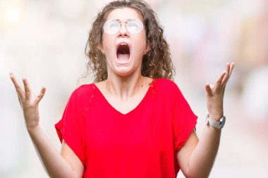 Güzel esmer kıvırcık saçlı Genç kız üzerinde gözlük takan arka plan deli izole ve deli bağırarak ve agresif ifade ve silah kaldırdı bağırıyor. Hayal kırıklığı kavramı.