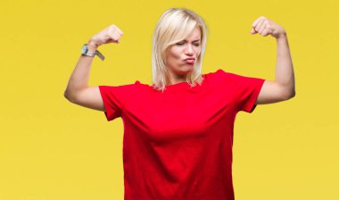 Kol kasları gururlu gülümseyen gösterilen izole arka plan üzerinde kırmızı t-shirt giyen genç güzel sarışın bir kadın. Fitness kavramı.