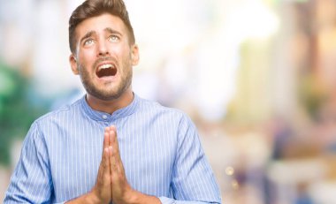 Yakışıklı delikanlı yalvarıyor ve umut ifade yüzünde çok duygusal ve endişe ile birlikte elleriyle dua izole arka plan üzerinde. Bağışlanmak. Din kavramı.