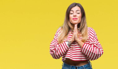 Genç güzel kadın rahat çizgili kış kazak yalvarıyor ve umut ifade yüzünde çok duygusal ve endişe ile birlikte elleriyle dua izole arka plan üzerinde. Bağışlanmak. Din kavramı.