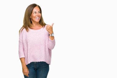 Seyir ve başparmak yanında yukarıyı mutlu yüz ile gülümseyen izole arka plan üzerinde kış kazak giyen güzel orta yaş yetişkin kadın.