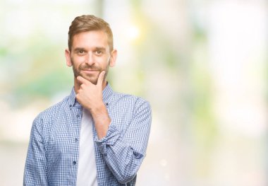 Emin çapraz kollar ve çeneme kaldırdı el ile gülümseme ile kameraya bakarak izole arka plan üzerinde beyaz t-shirt giyen genç yakışıklı adam. Pozitif düşünce.