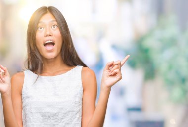 Genç Asyalı kadın izole arka plan üzerinden hayran ve yukarıya bakıp parmakları ile işaret şaşırttı ve silah kaldırdı.