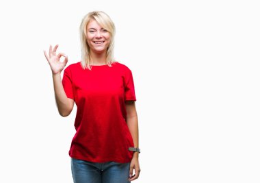 İzole arka plan el ve parmaklar ok işaretiyle yapıyor olumlu gülümseyen üzerinde kırmızı t-shirt giyen genç güzel sarışın kadın. Başarılı ifade.
