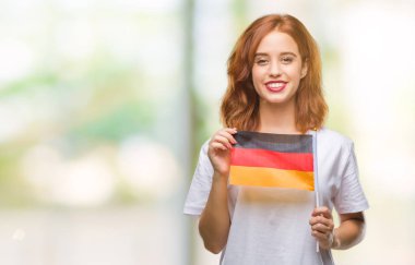 Almanya bayrağı izole arka plan üzerinde duran ve diş gösterilen kendine güvenen bir gülümsemeyle gülümseyerek mutlu bir yüz tutan genç güzel kadın