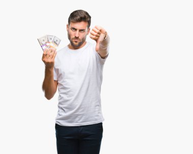 Kızgın yüz, eksi işareti aşağı antipati başparmak ile gösterilen, ret kavramı ile izole arka plan üzerinde dolar yığını tutan genç yakışıklı adam