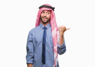 Keffiyeh seyir ve başparmak yanında yukarıyı mutlu yüz ile gülümseyen izole arka plan üzerinde giyen genç yakışıklı Arap iş adamı.