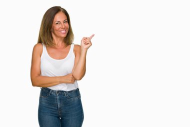 Kameraya bakarak yan el ve parmak ile işaret eden güzel orta yaş rahat yetişkin kadın yüzünde kocaman bir gülümseme ile izole arka plan.