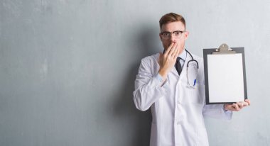 Hata, korku, sessizlik içinde gizli kavramı korkmuş ifade için utanç ile gri grunge duvar panosu kapak ağız elle tutan genç redhead Doktor adam şok