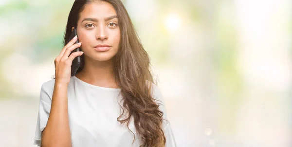 年轻美丽的阿拉伯妇女在电话里通过孤立的背景交谈 聪明的脸上自信的表情思考严肃 — 图库照片