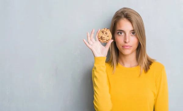 Hermosa Mujer Joven Sobre Grunge Gris Pared Comer Chocolate Chip —  Fotos de Stock