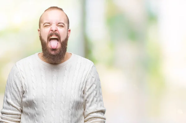 年轻的高加索嬉皮士男子穿着冬季毛衣在孤立的背景伸出舌头出来高兴与有趣的表达 情感概念 — 图库照片