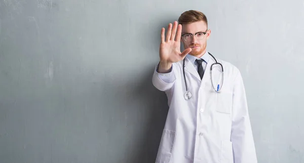 Joven Médico Pelirrojo Hombre Sobre Pared Grunge Gris Con Mano —  Fotos de Stock