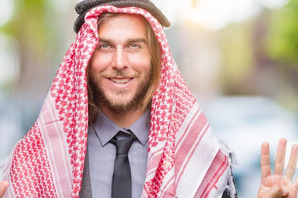 Young handsome arabian man with long hair wearing keffiyeh over isolated background showing and pointing up with fingers number nine while smiling confident and happy.