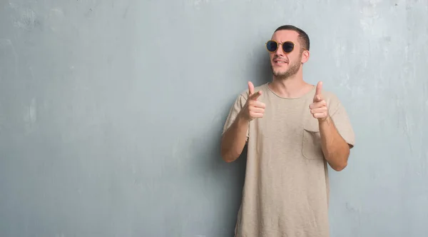 Young Caucasian Man Grey Grunge Wall Wearing Sunglasses Pointing Fingers — Stock Photo, Image