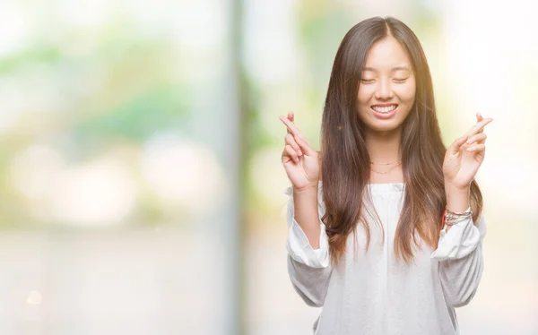 年轻的亚洲妇女在孤立的背景微笑交叉手指 — 图库照片
