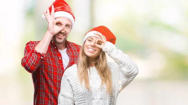 手が笑顔で のジェスチャーを行う分離の背景にクリスマスの帽子をかぶって恋カップル目の幸せそうな顔で指を通して見る — ストック写真