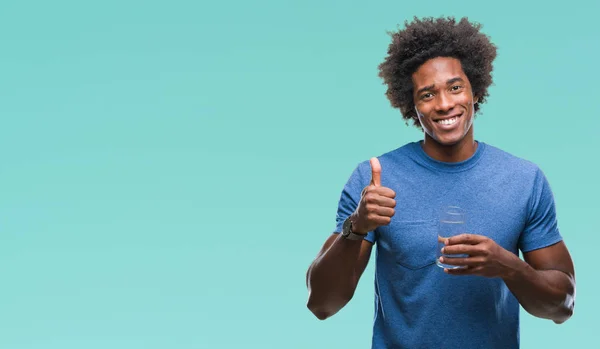 Afro american man drinking glass of water over isolated background happy with big smile doing ok sign, thumb up with fingers, excellent sign