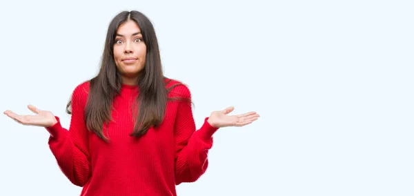 Junge Schöne Hispanische Tragen Roten Pullover Ahnungslos Und Verwirrt Ausdruck — Stockfoto