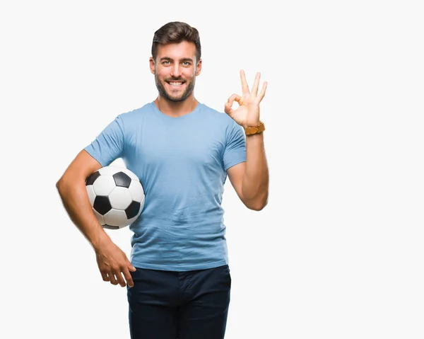 優秀なシンボルの指で サインをして孤立した背景にサッカー サッカー ボールを保持している若いハンサムな男 — ストック写真