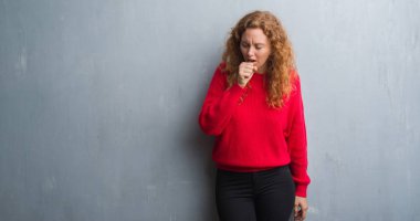 Soğuk veya bronşit için kırmızı kazaklı duygu hasta ve öksürük semptom olarak takmış gri grunge duvarın üzerinden genç Kızıl saçlı kadın. Sağlık kavramı.