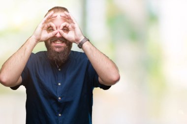 Genç beyaz hipster adam izole arka plan, dilini parmaklarının arasından baktığını yapışmasını dürbün gibi ok jest yapıyor. Deli ifade.