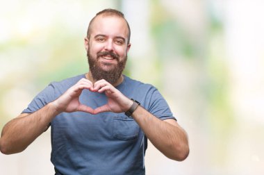 Genç beyaz hipster adam aşık kalp simgesi ve elleriyle şekil gösteren gülümseyen izole arka plan üzerinde. Romantik kavramı.