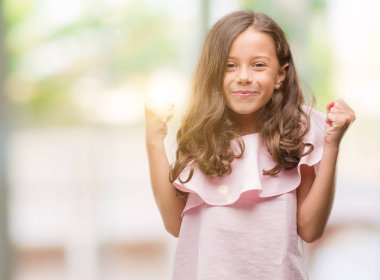 Esmer Latin kız kutlayan pembe elbise giyiyor şaşırttı ve başarı için kaldırdı kollarını açarak hayrete ve gözleri açık. Kazanan kavramı.