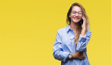 Genç güzel sarışın iş kadını kullanan Smartphone üzerinden arama arka plan ayakta ve diş gösterilen kendine güvenen bir gülümsemeyle gülümseyerek mutlu bir yüz ile izole